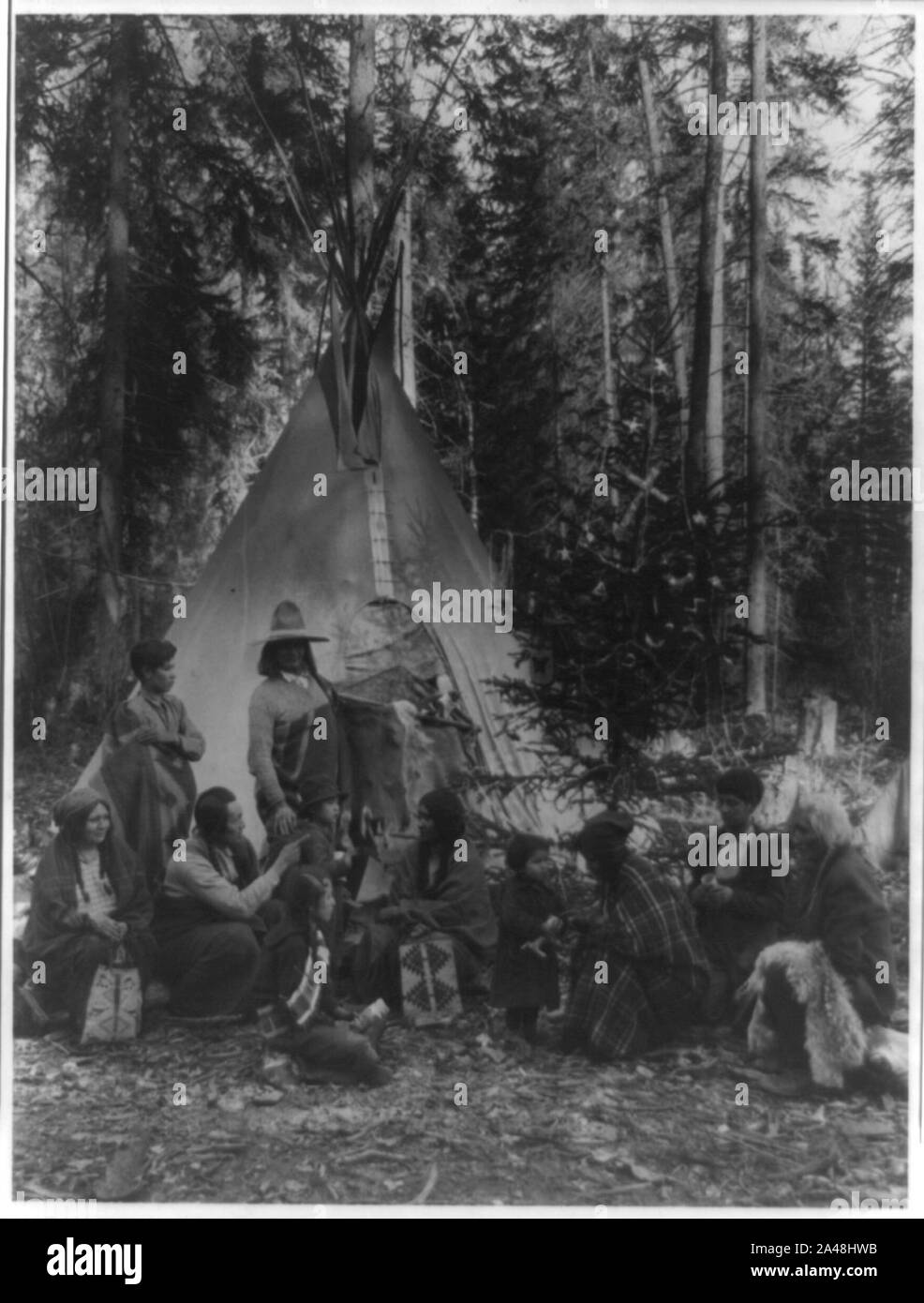 Flathead Indians holding pre-Christmas family gatherings on the west side of Glacier National Park, in the dense forest of evergreen trees that skirt the Rocky Mountains Stock Photo