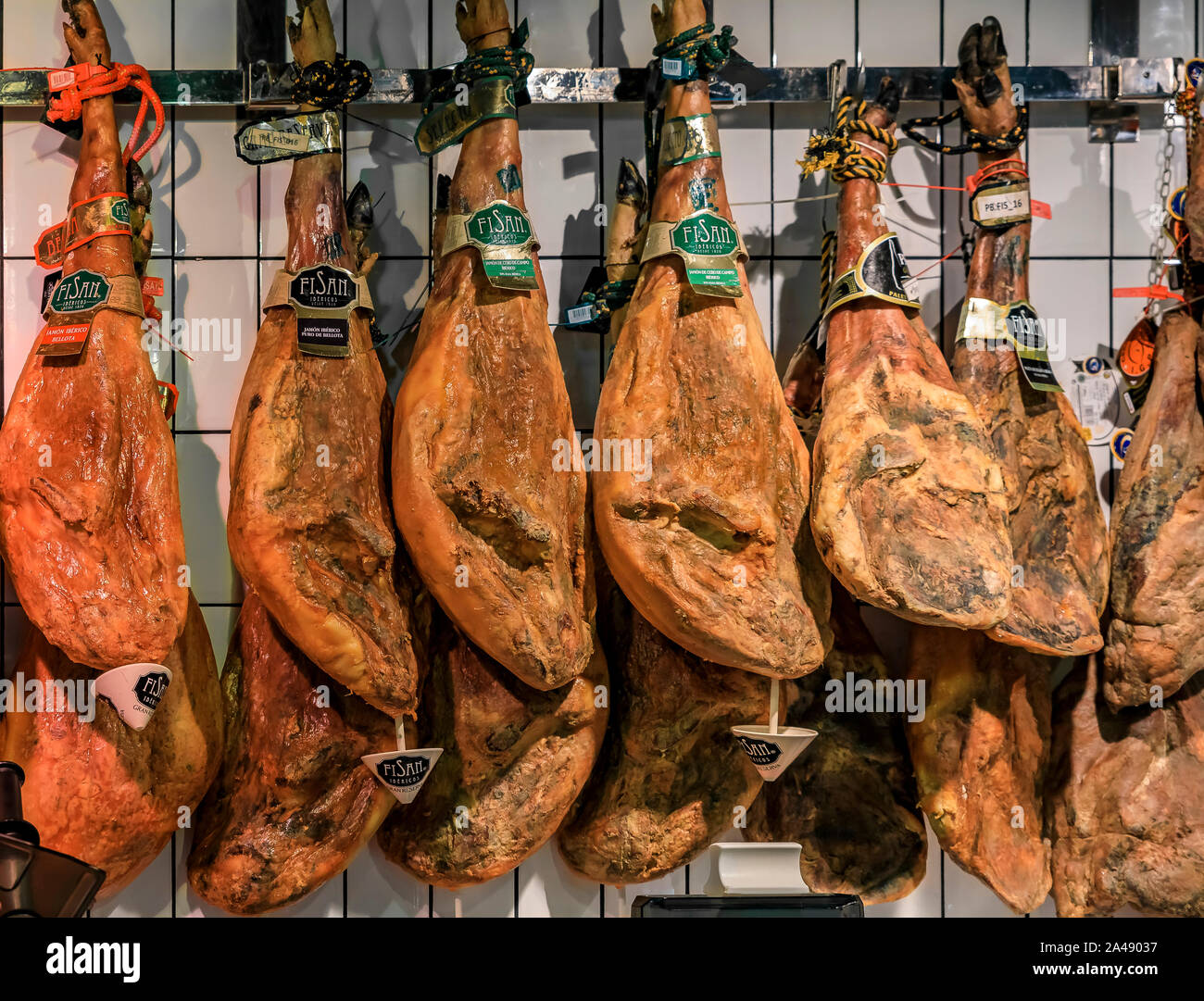 Madrid, Spain - June 4, 2017: Multiple whole bone-in legs of Spanish serrano iberico ham on display at a local market Stock Photo