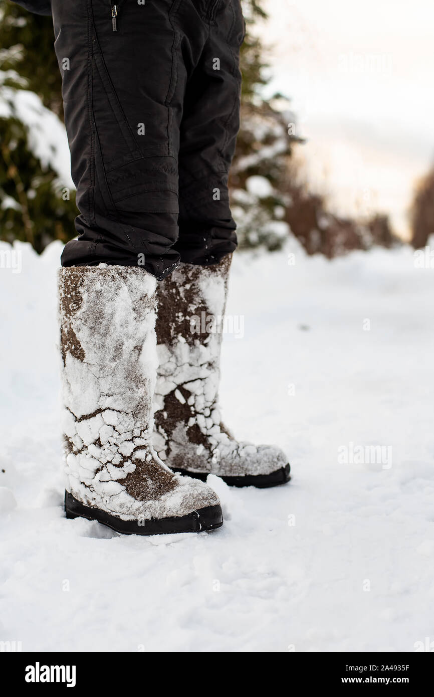 Feet in warm, comfortable felt shoes with snow stuck to them after a walk  through the snowdrifts in the forest are on a cleared road, against a  blurre Stock Photo - Alamy