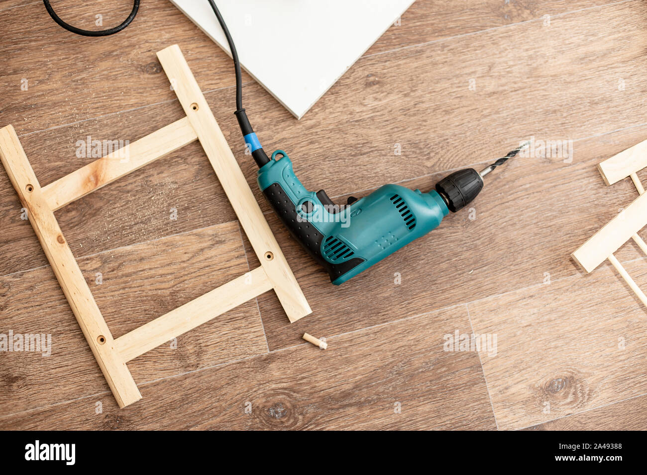 Power drill and wood products and constructions lay on a floor ready to