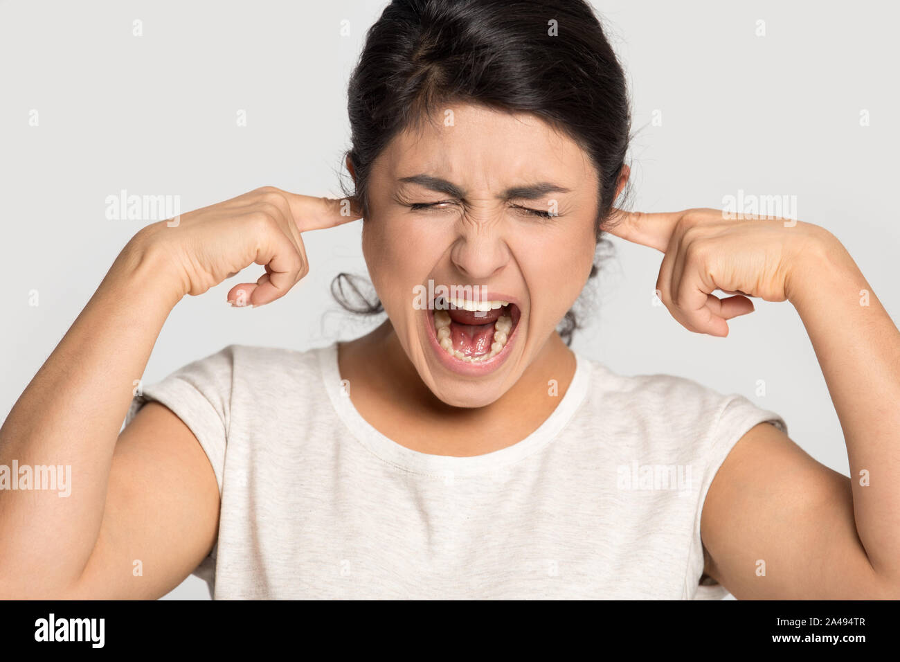 Mad ethnic girl scream bothered by disturbing sound Stock Photo