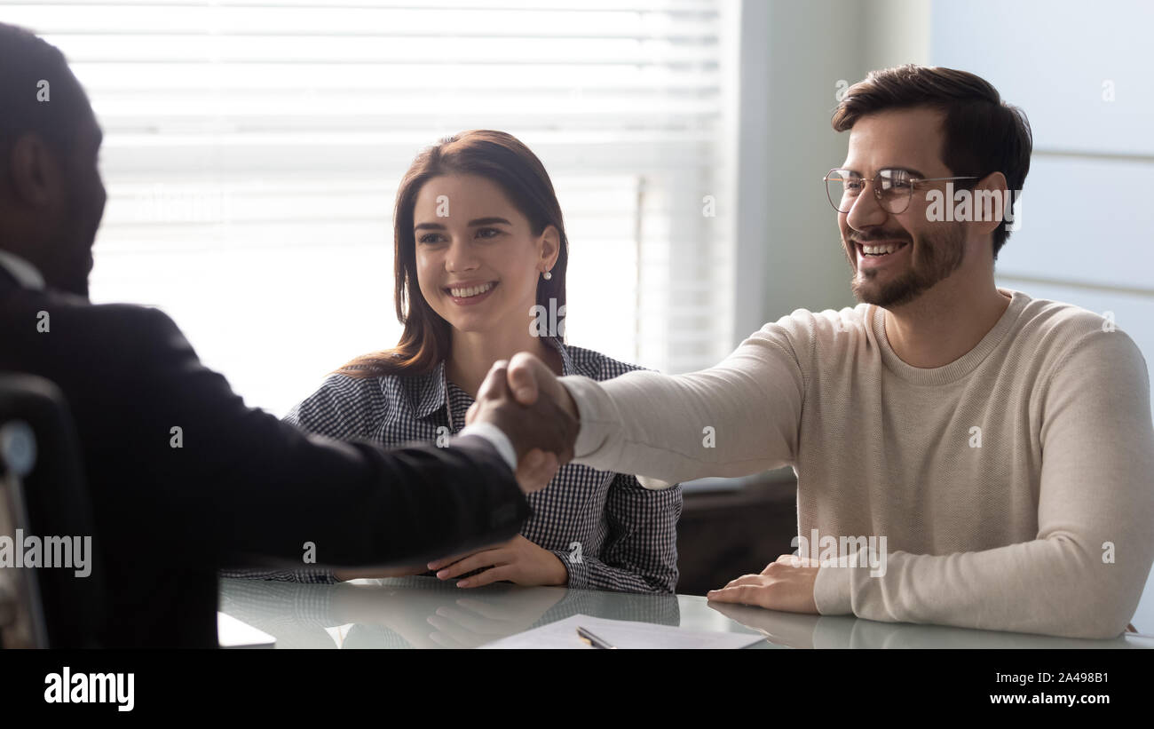 Smiling young man shaking hands with financial advisor. Stock Photo