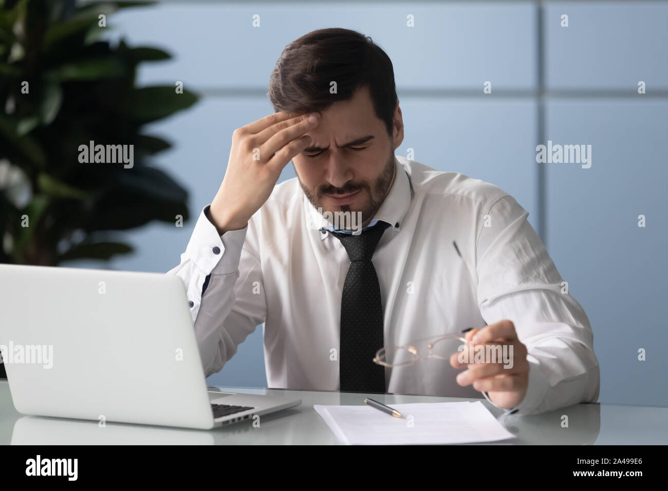 Frustrated young manager suffering from strong head ache. Stock Photo