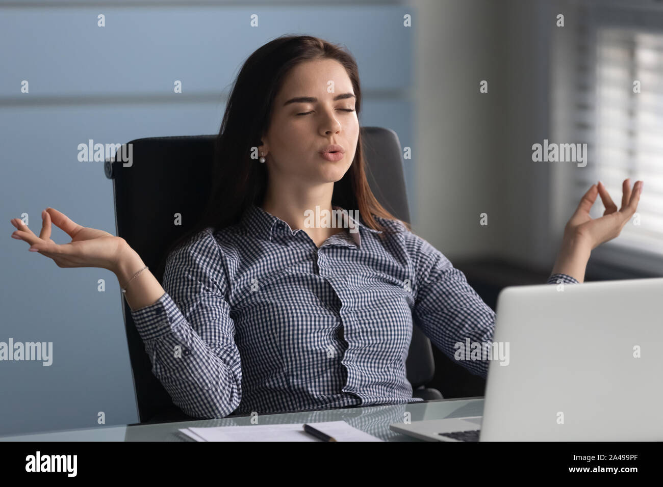Young female worker making yoga breathing exercises. Stock Photo