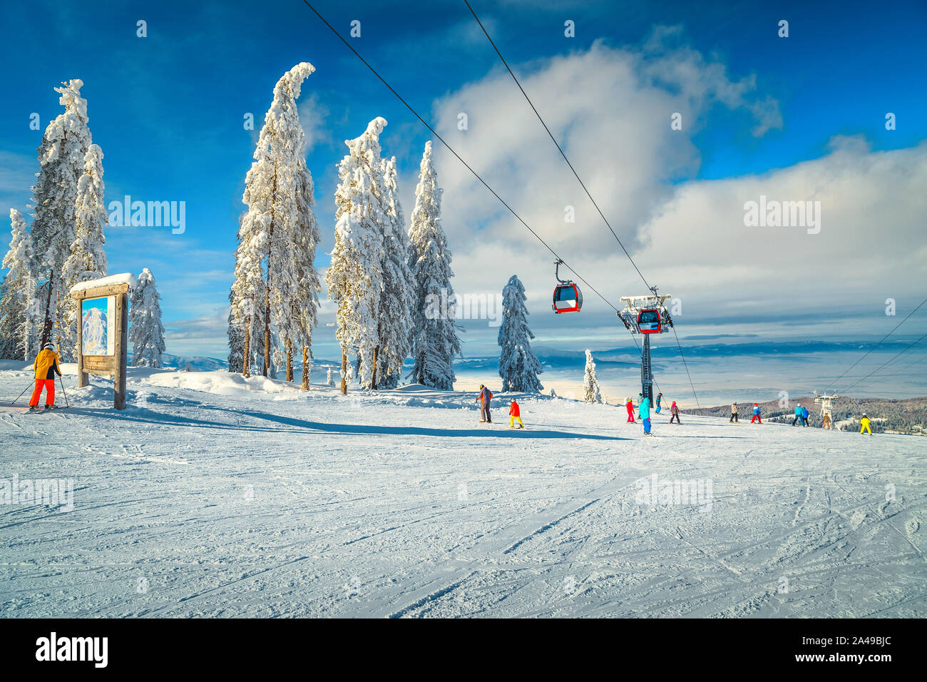 Spectacular snow covered trees and winter ski resort with colorful fast ski lifts. Skiers downhill on the ski slopes in Poiana Brasov ski resort, Tran Stock Photo