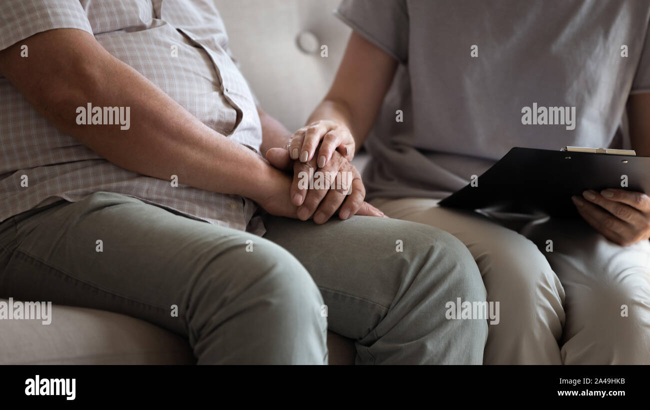 Nurse holding clipboard and touch hands of patient male indoors Stock Photo