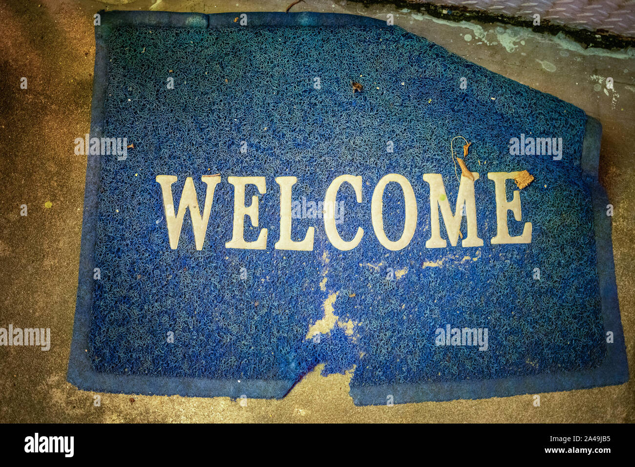 welcome Mat at the entrance, dirty old worn and worn to the holes, blue, shooting from above, close-up. Stock Photo