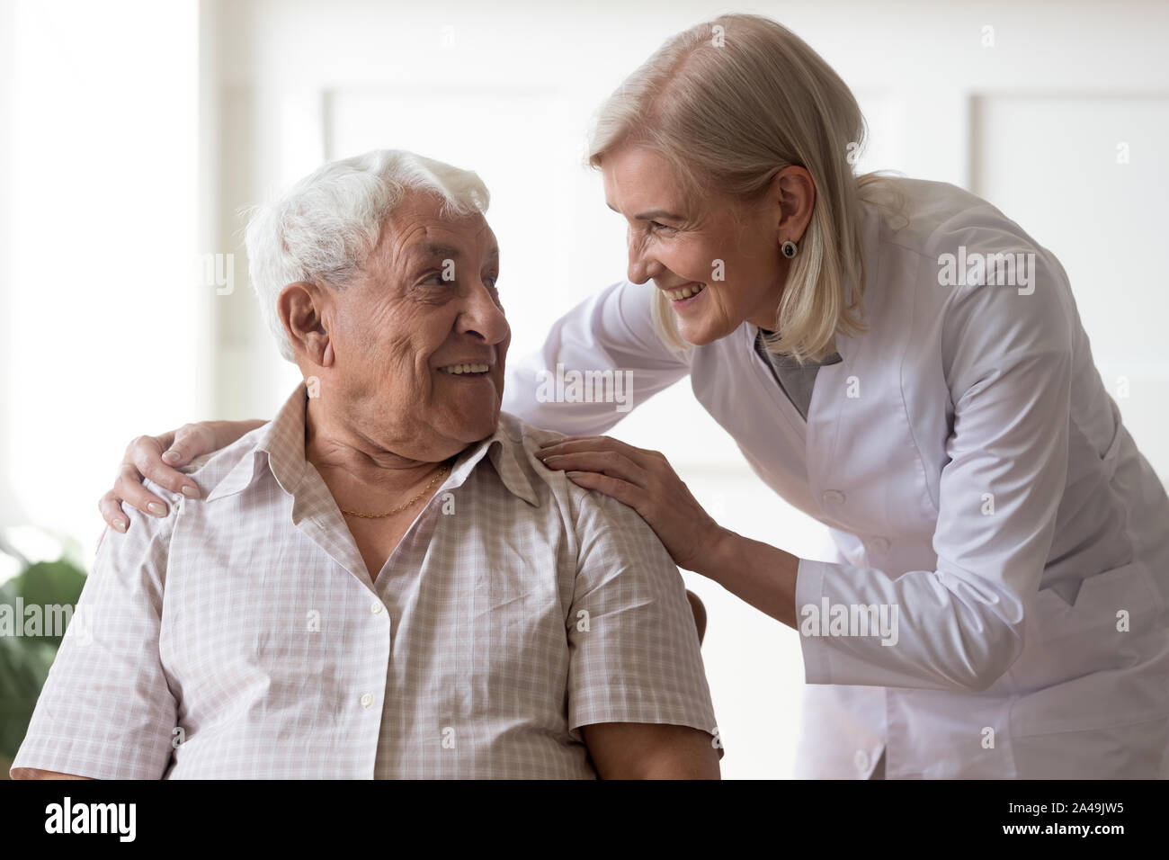 Senior man clinic patient interacting with nurse in white coat Stock Photo