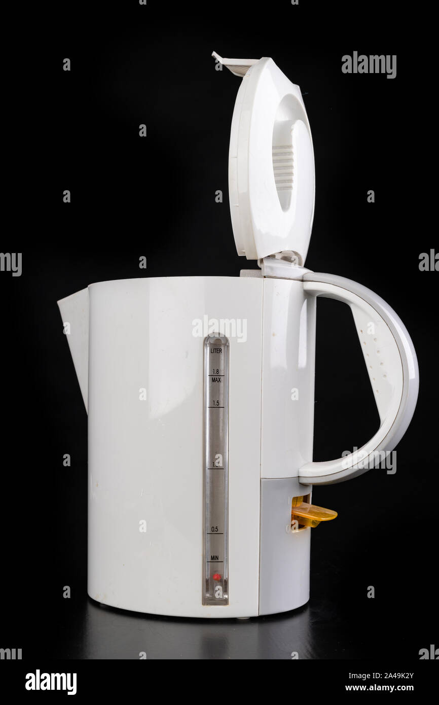 Plastic electric kettle for boiling water. Kitchen accessories on a dark table. Black background