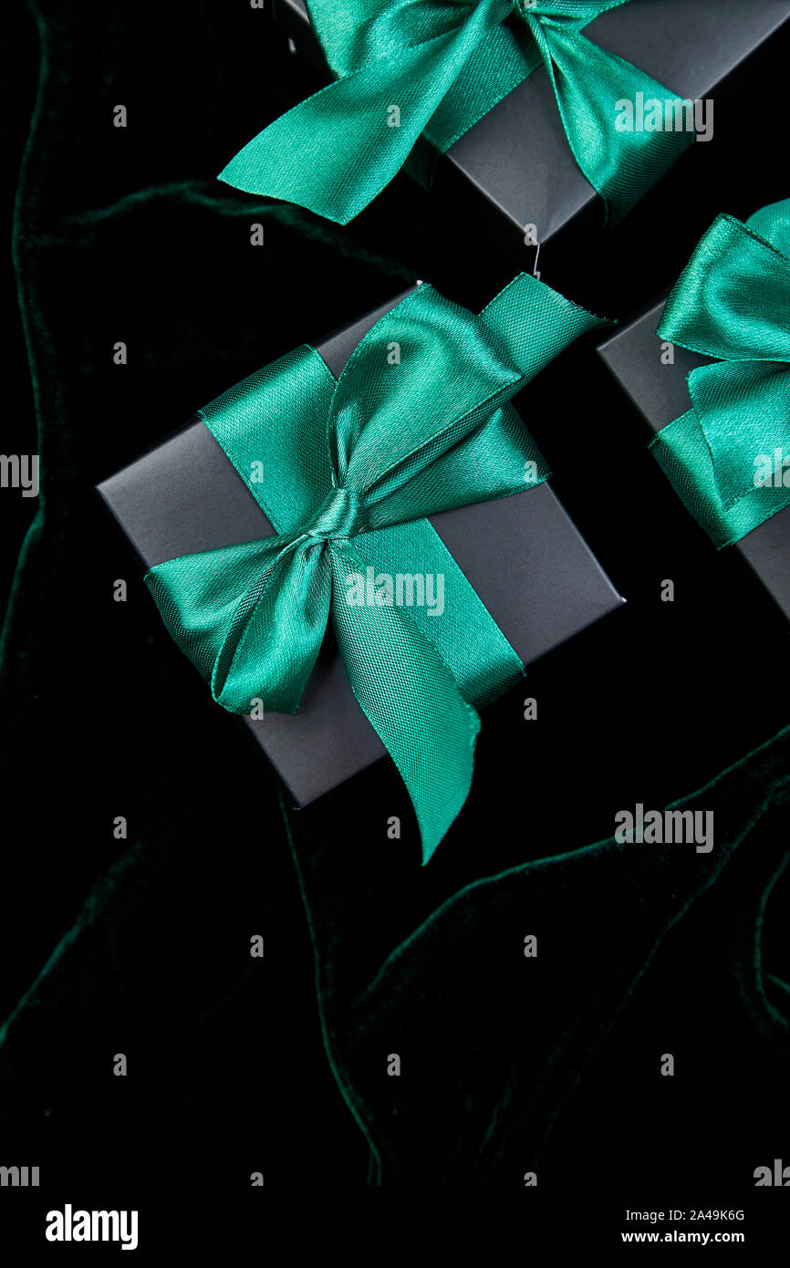 Luxury black gift boxes with green ribbon on shine velvet background ...