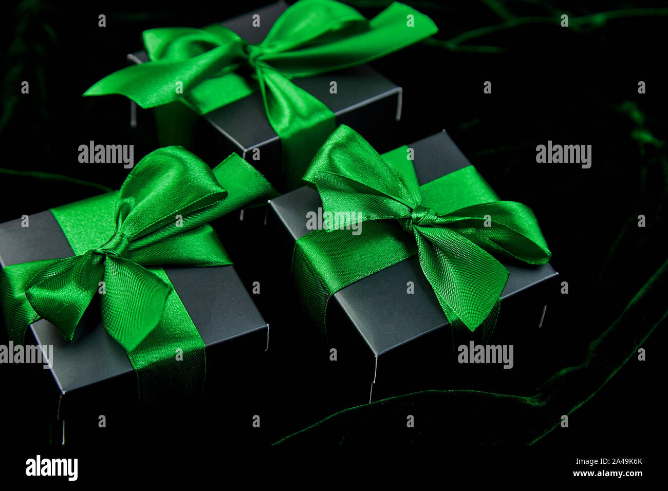 Luxury black gift boxes with green ribbon on shine velvet background ...