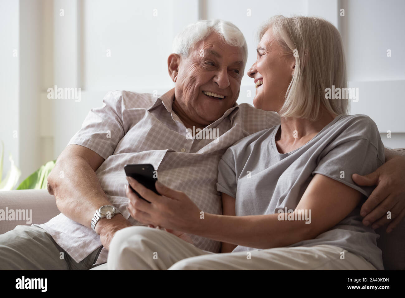 Elderly husband and middle-aged wife having fun using smartphone Stock Photo