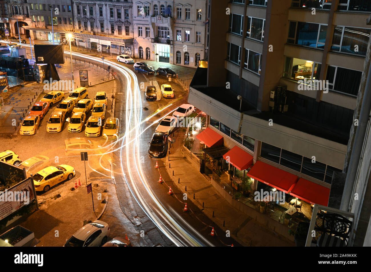 Istanbul, Turkey - October 7, 2019: Taxis wait for fares in a lot next to a winding road in a long-exposure nighttime shot. Stock Photo