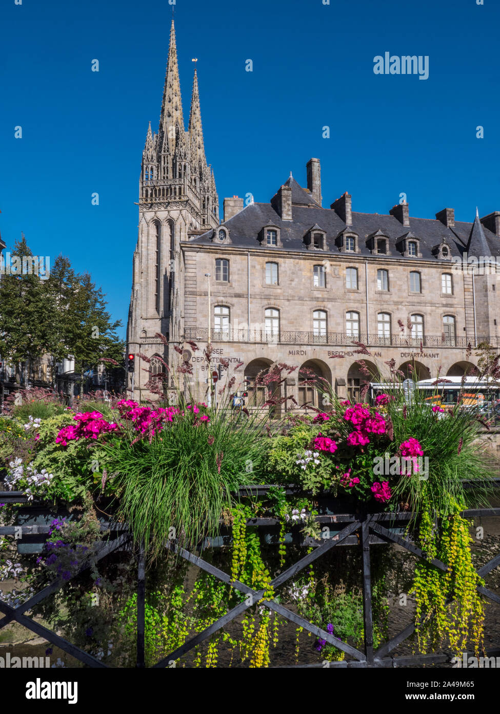 Quimper Musée des Beaux-Arts and Saint Corentin Quimper Cathedral behind viewed from River Odet with street flowers in foreground Brittany France Stock Photo