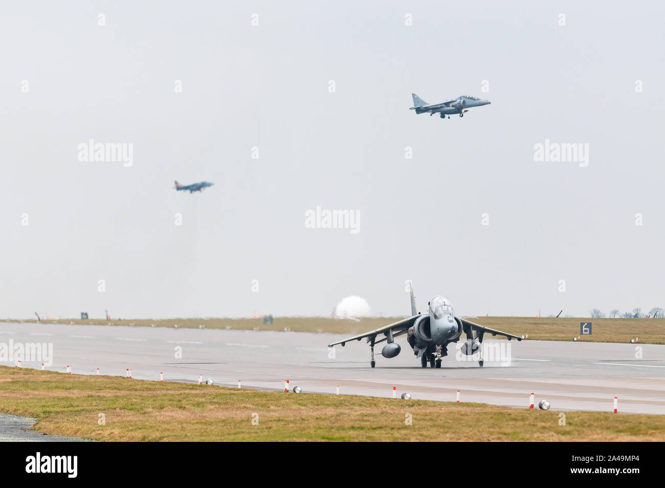 RAF Harrier GR9 taxiing on runway with Harriers landing behind after final flight on 15th December 2010, RAF Cottesmore Stock Photo