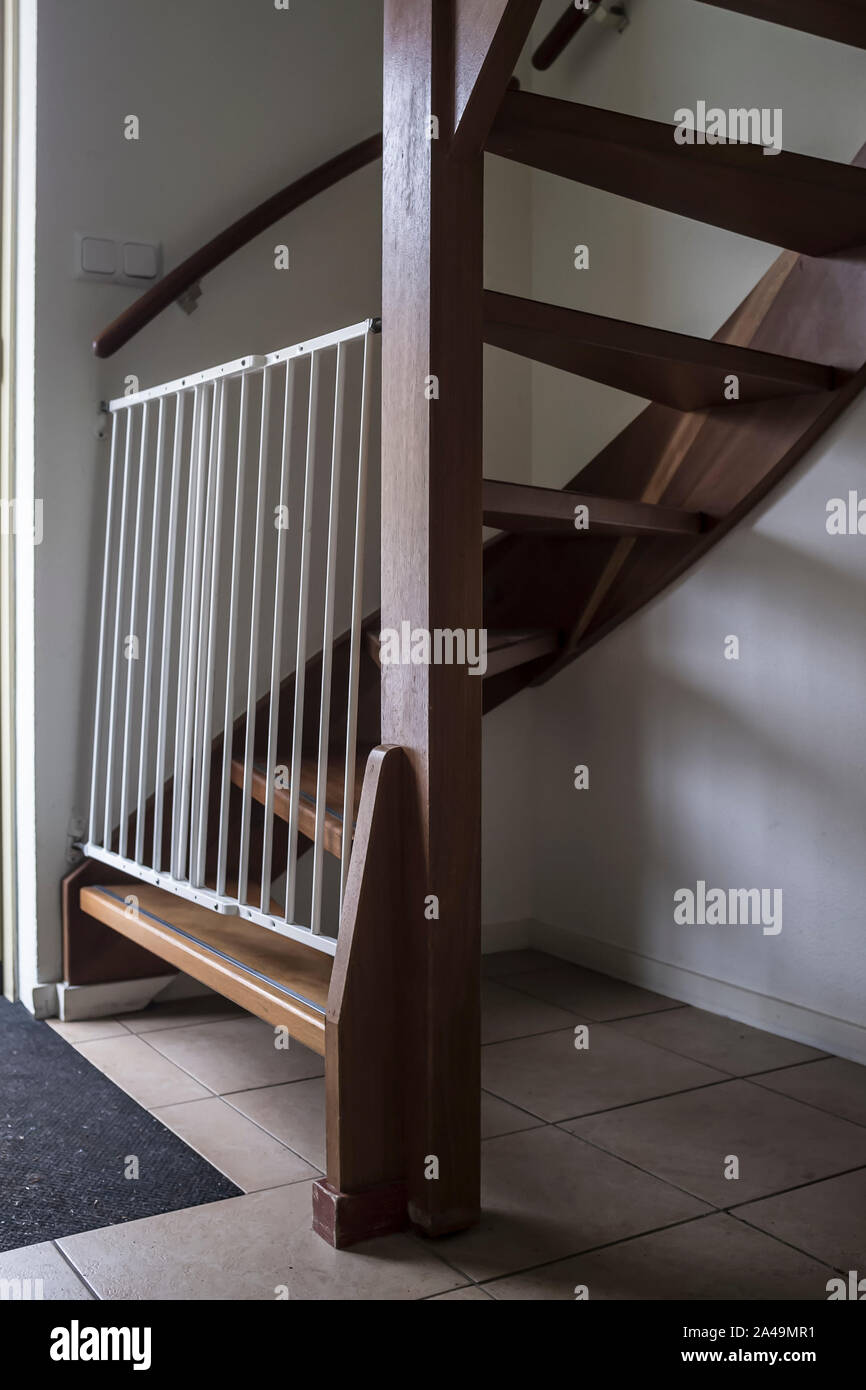 Closed white security gate stands at the bottom of a spiral wooden