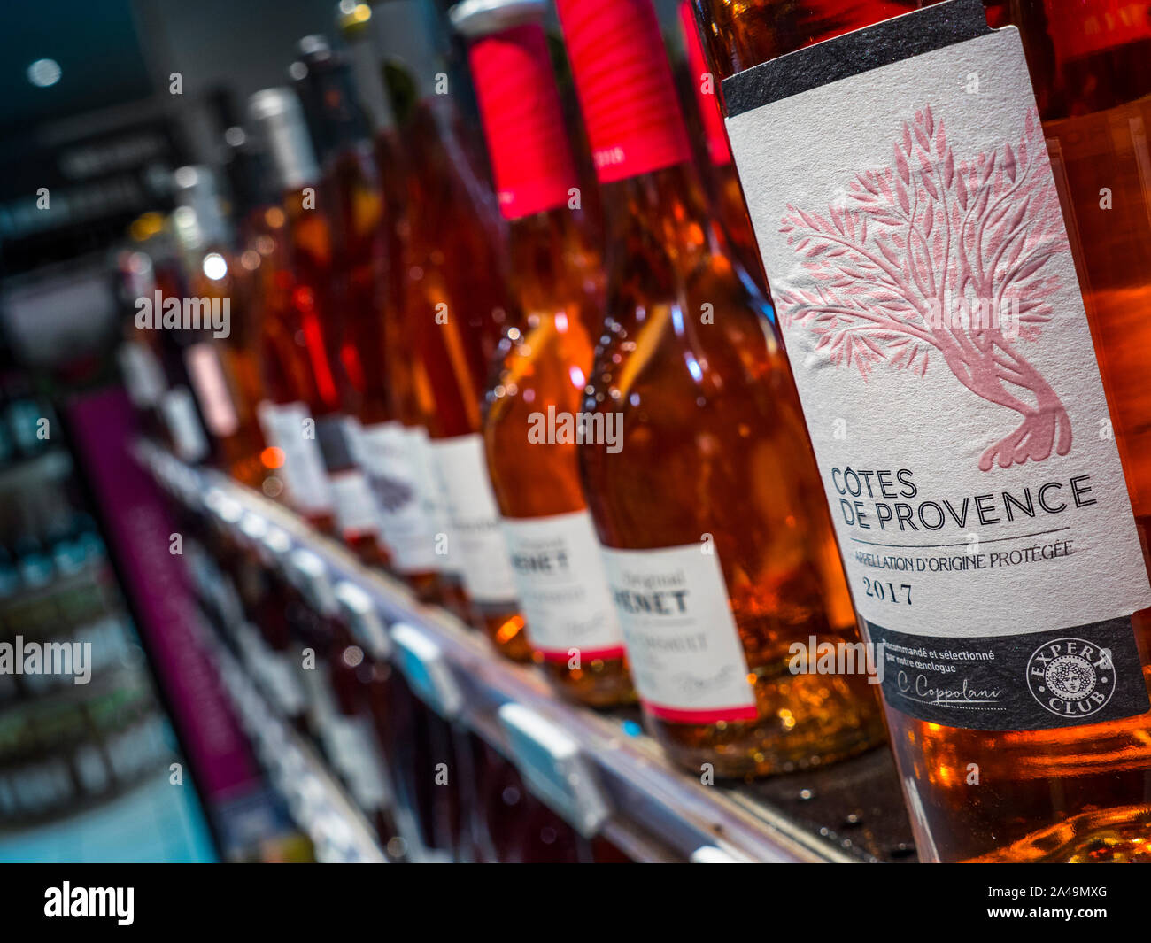 Côtes de Provence Rosé wine bottle label featured in foreground, with other rosé wine bottles behind on French wine shop store shelf display for sale Stock Photo