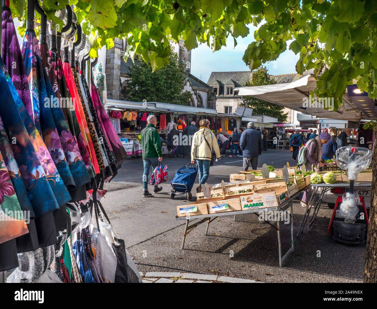 FRANCE VILLAGE STREET MARKET Moëlan sur Mer Market Brittany small charming local French church square weekly general produce/clothing market.  The life blood of the local community Brittany France Stock Photo