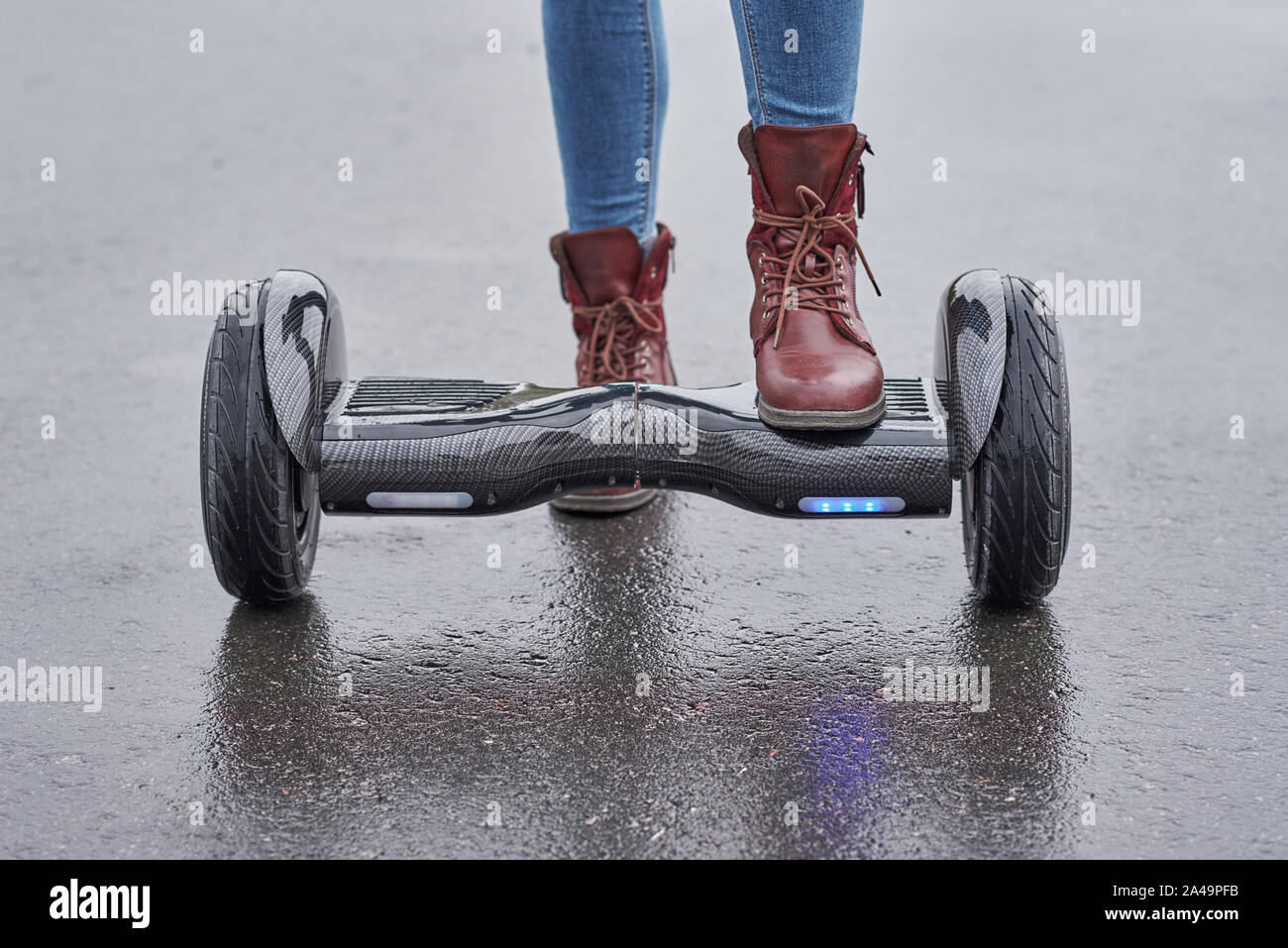 Woman using hoverboard on asphalt road, close up. Feet on electrical scooter outdoor Stock Photo