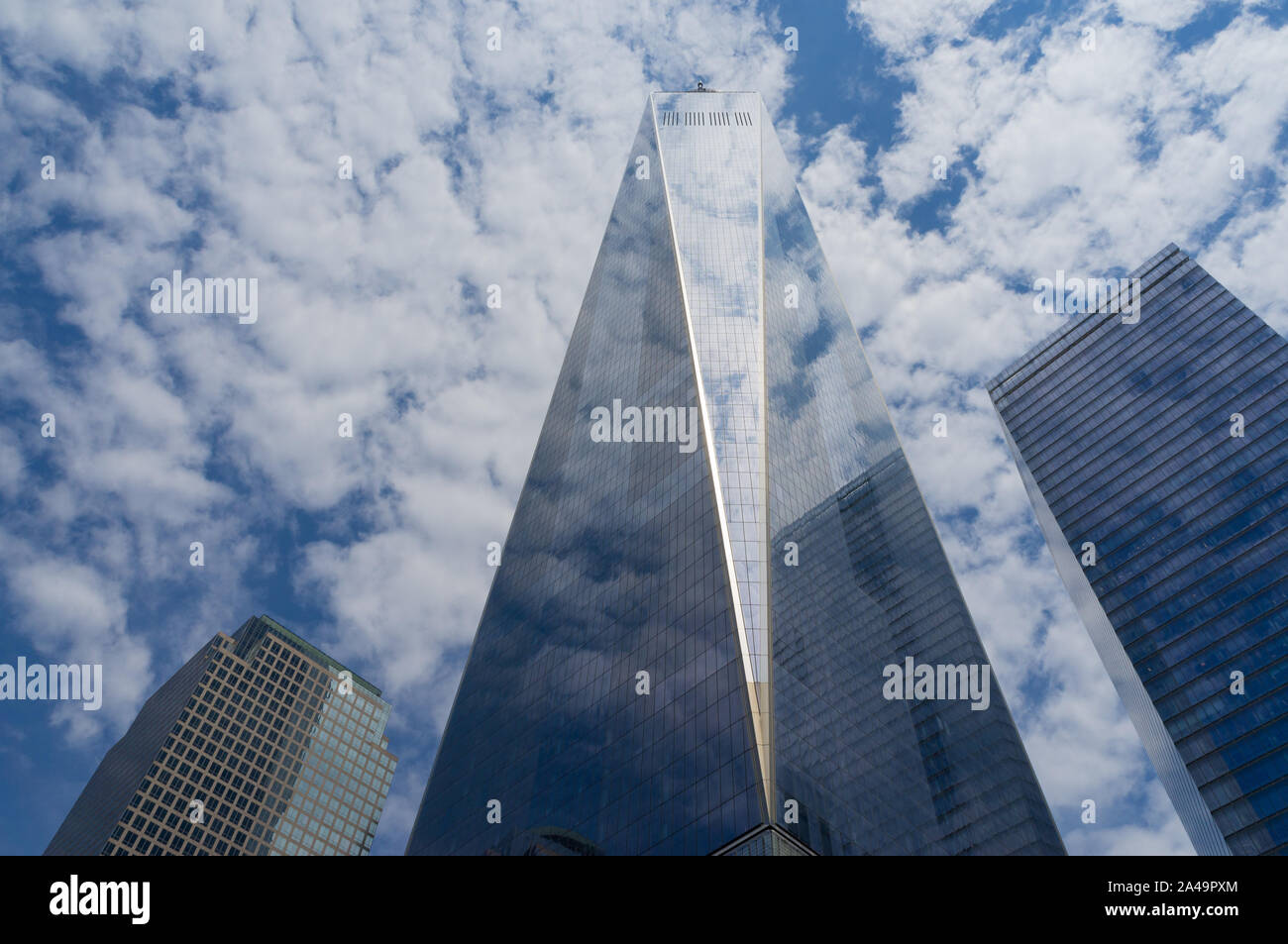 One World Trade Center in Manhattan, New York on a sunny day, partially clouded with reflections of clouds in the glass facade Stock Photo