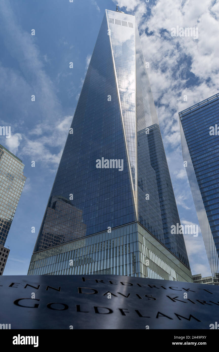 One World Trade Center in Manhattan, New York on a sunny day, partially clouded with reflections of clouds in the glass facade Stock Photo