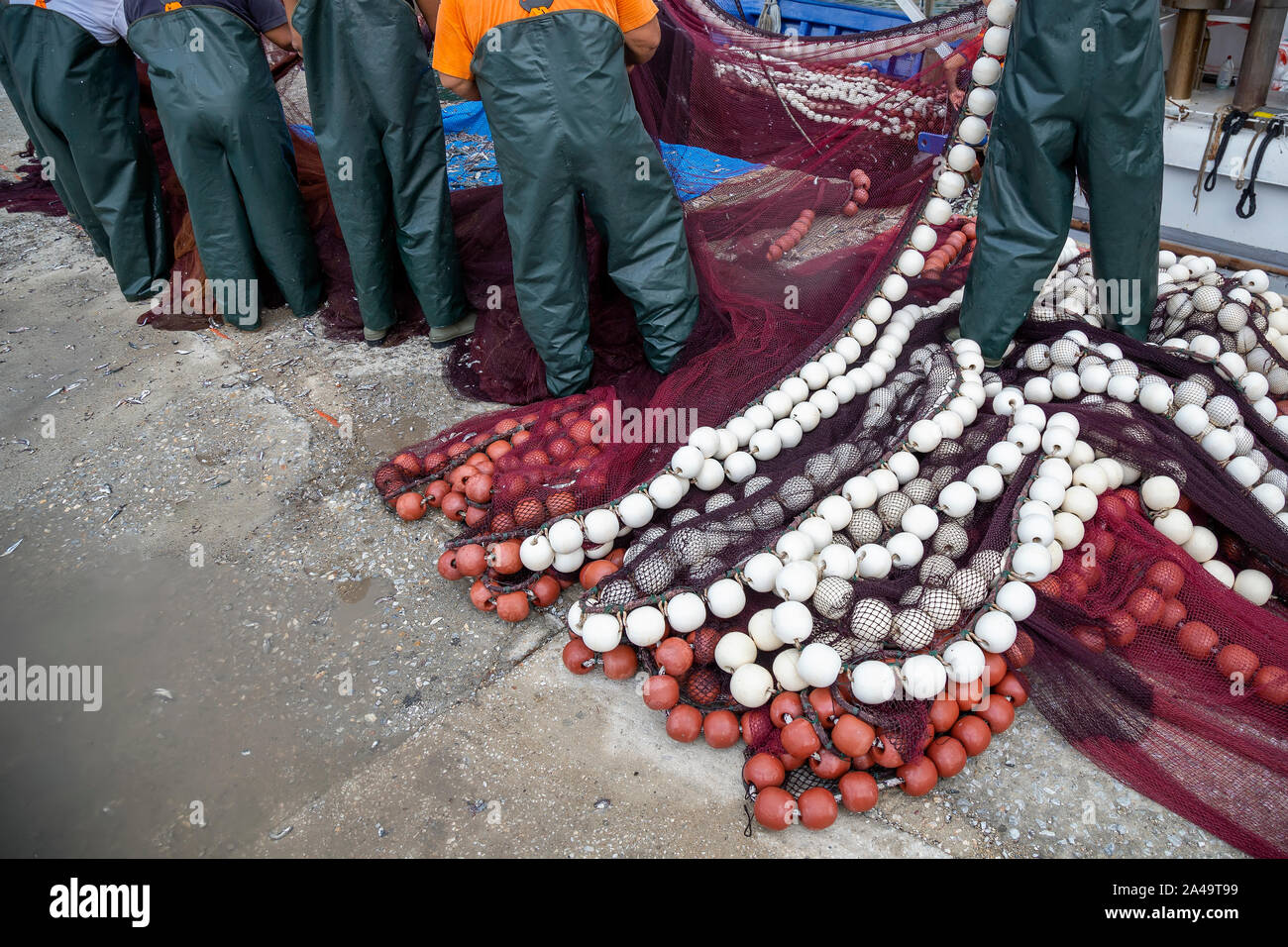Fishermen cleaning nets and spread on the ground of a fishing port