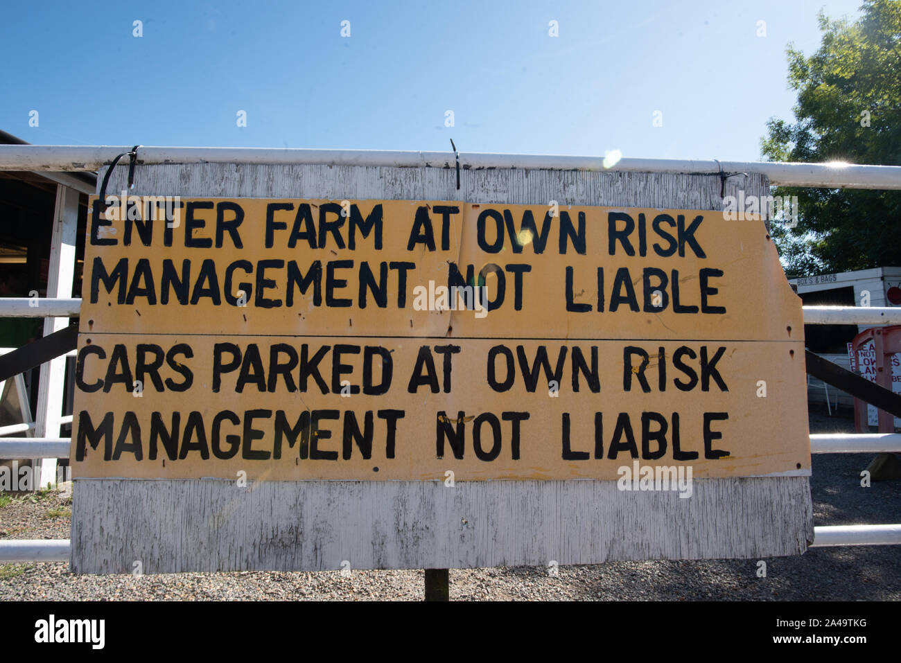 Kent, United Kingdom - September 15, 2019: A hand-painted yellow and black sign says “Enter Farm at Own Risk” and “Management Not Liable”. Stock Photo