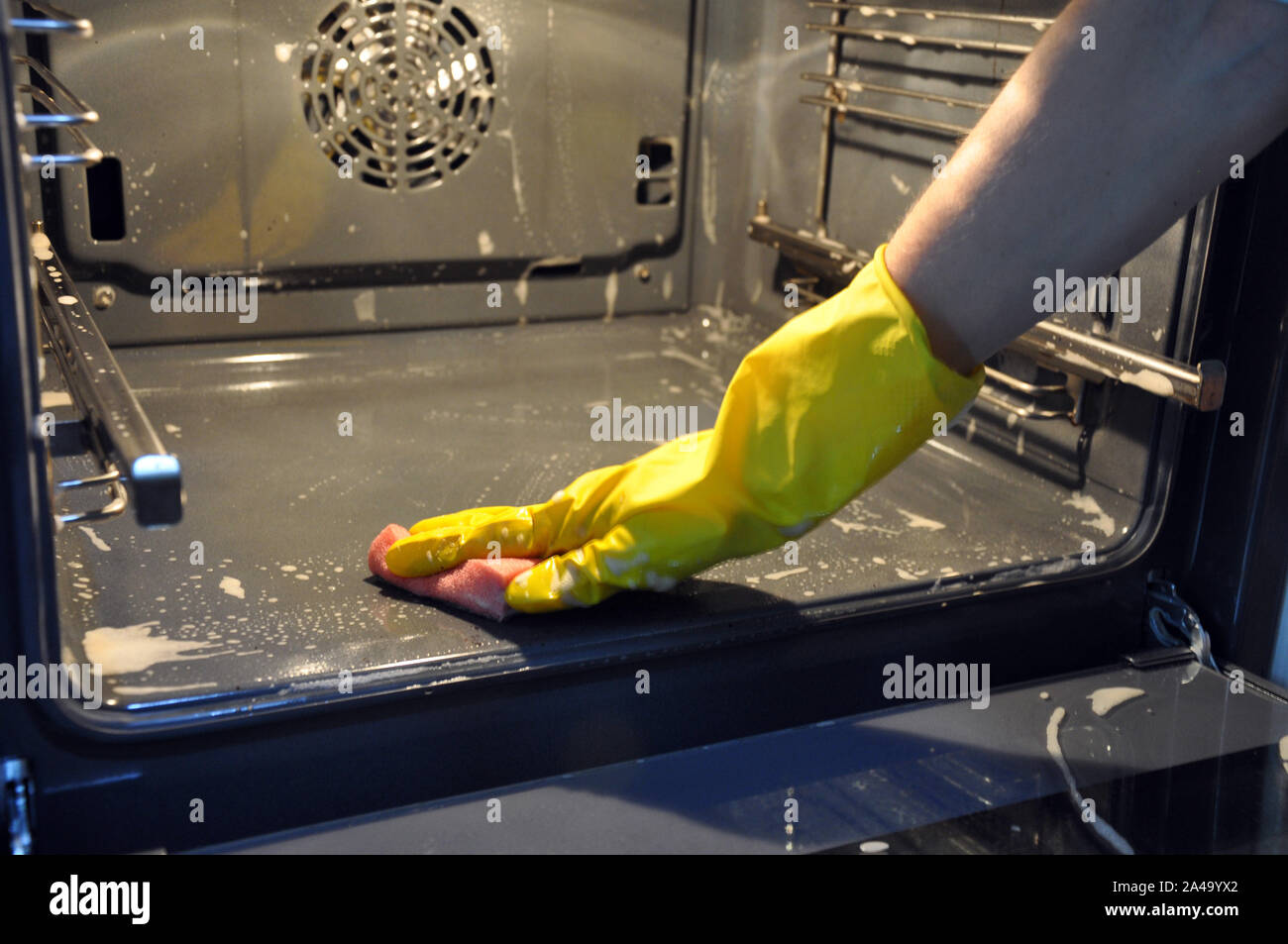 cleaning the oven in the kitchen. hand in a yellow economic glove. Stock Photo