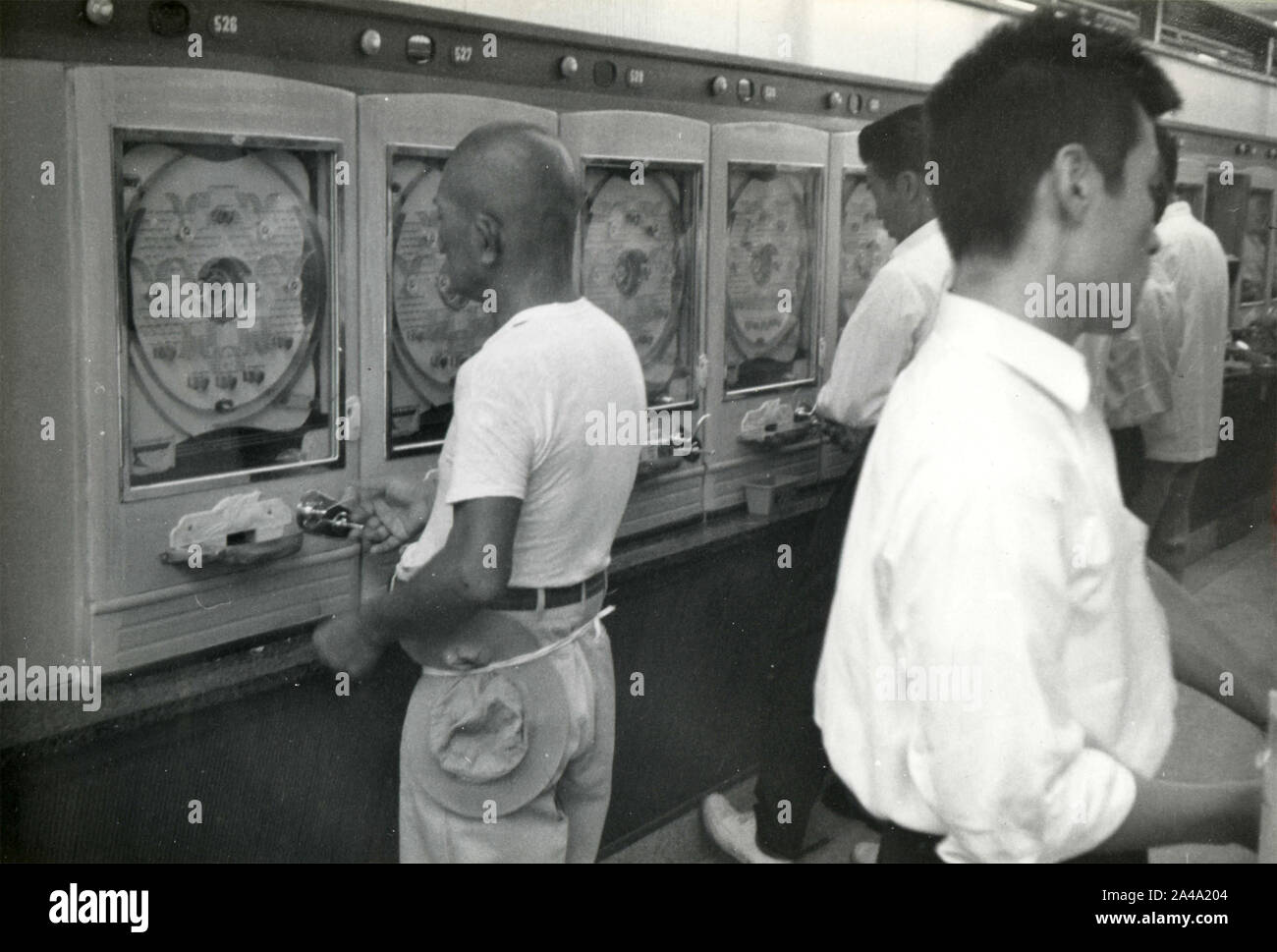 Gambles playing with old slot machines, Japan 1958 Stock Photo