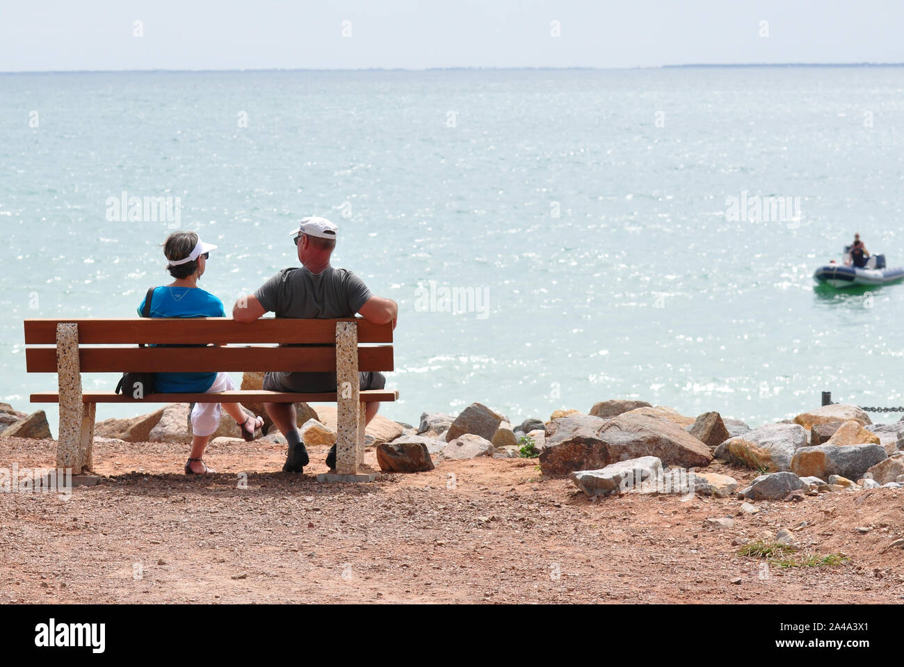 Couple on bench looking out to sea, France Stock Photo