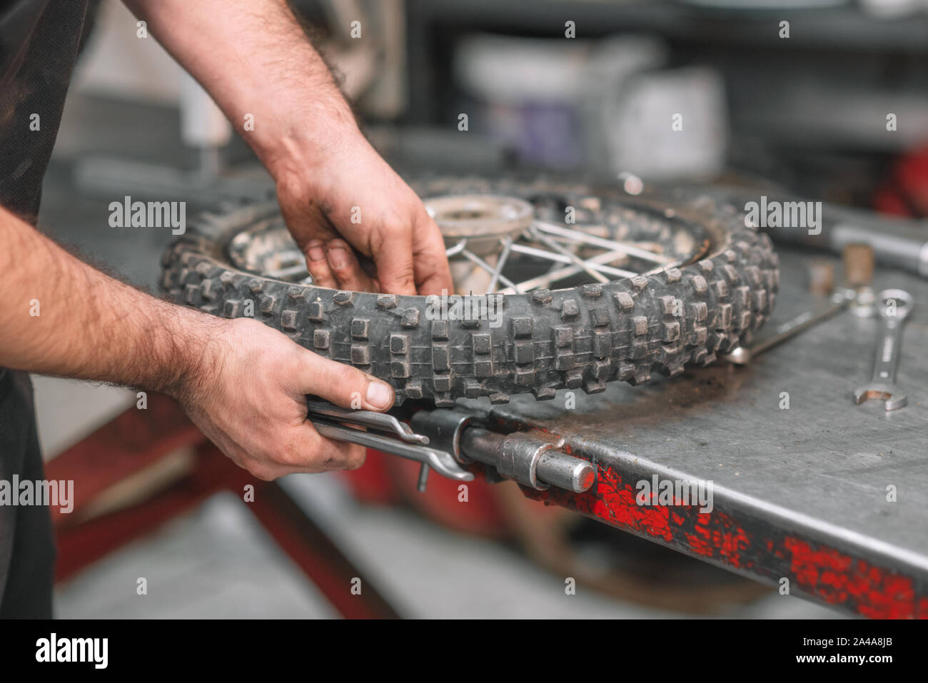 Mechanic repairing damaged motorcycle tire, in repair shop Stock Photo