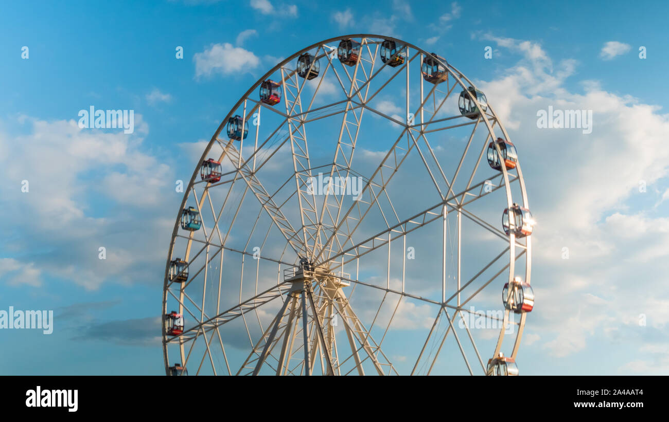 Rotating ferris wheel and white clouds, sunset cloudy sky Stock Photo ...