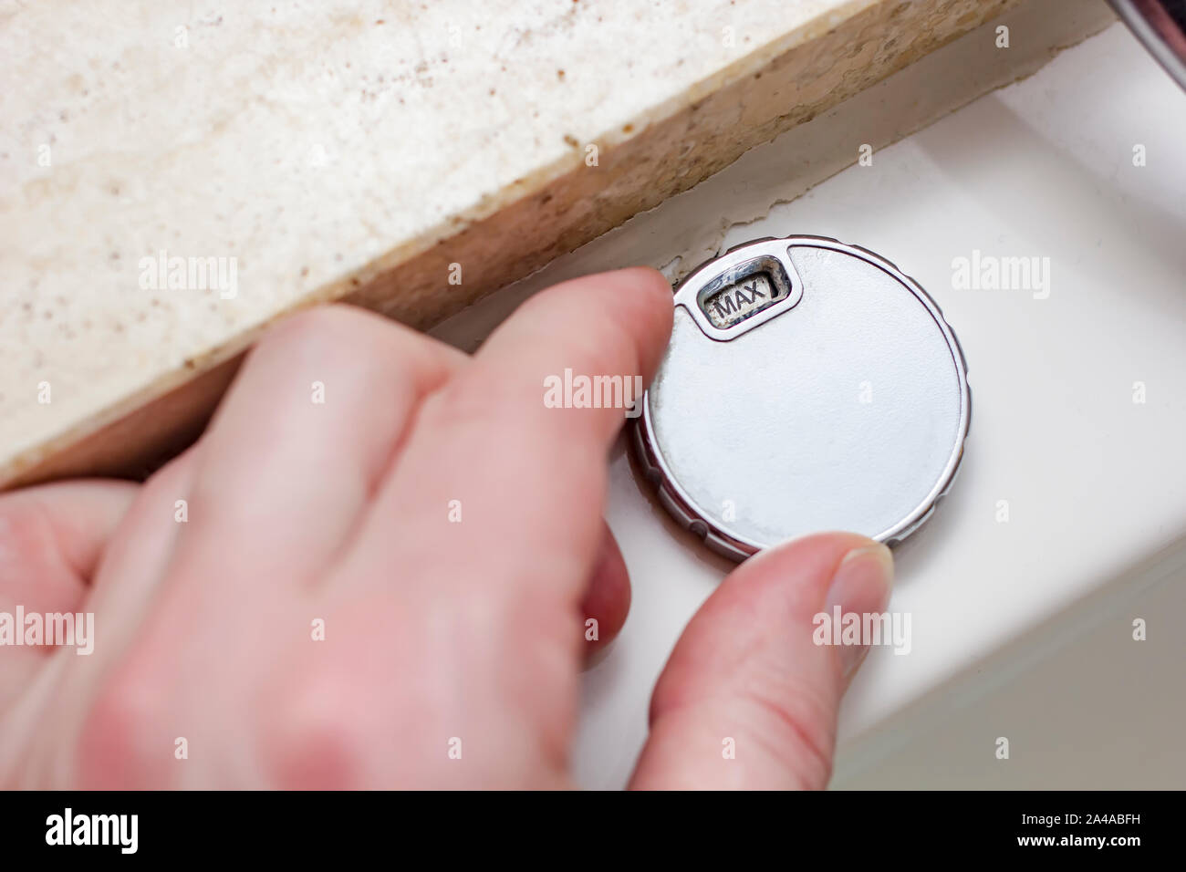 Male hand controls the modern, luxurious whirlpool bath and turns the valve to the value 'MAX'. Close-up. Stock Photo
