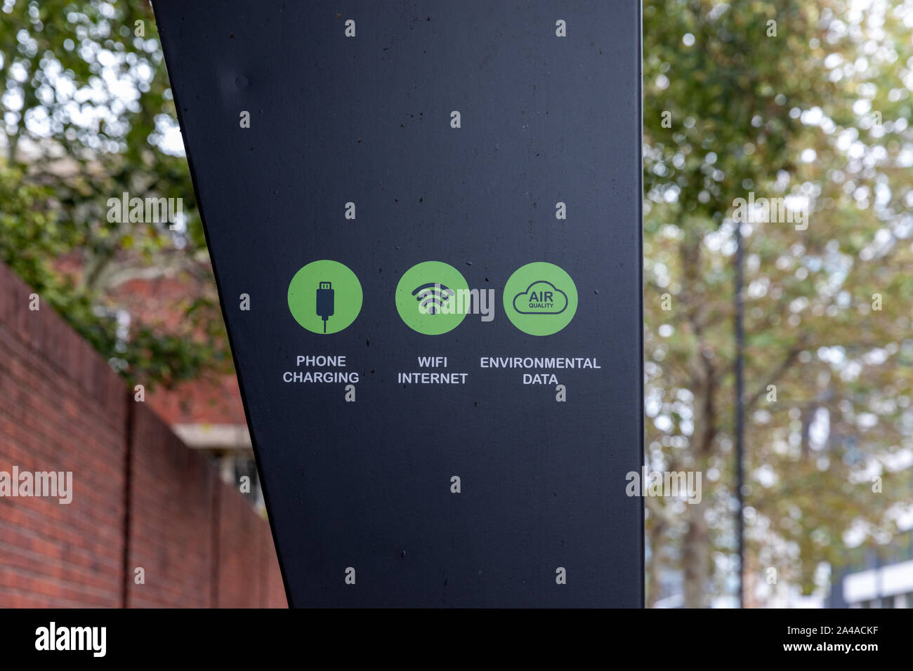 A Duolingo solar powered smart bench sign displaying phone charging, wifi internet and environmental data services on a city street in London. Stock Photo