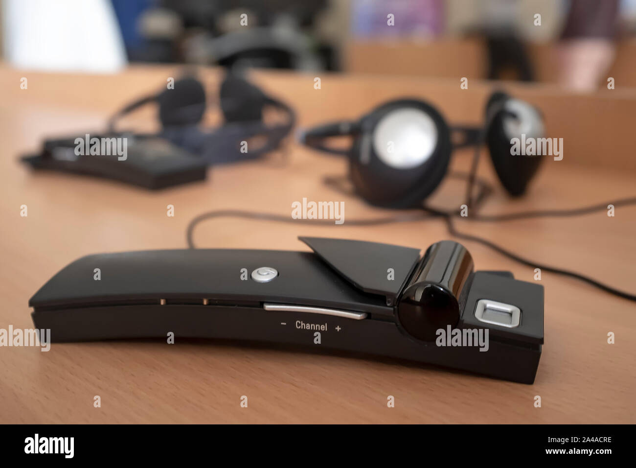Wireless simultaneous translation system with headphones lies on the table against the blurred background with another similar device during a lecture Stock Photo