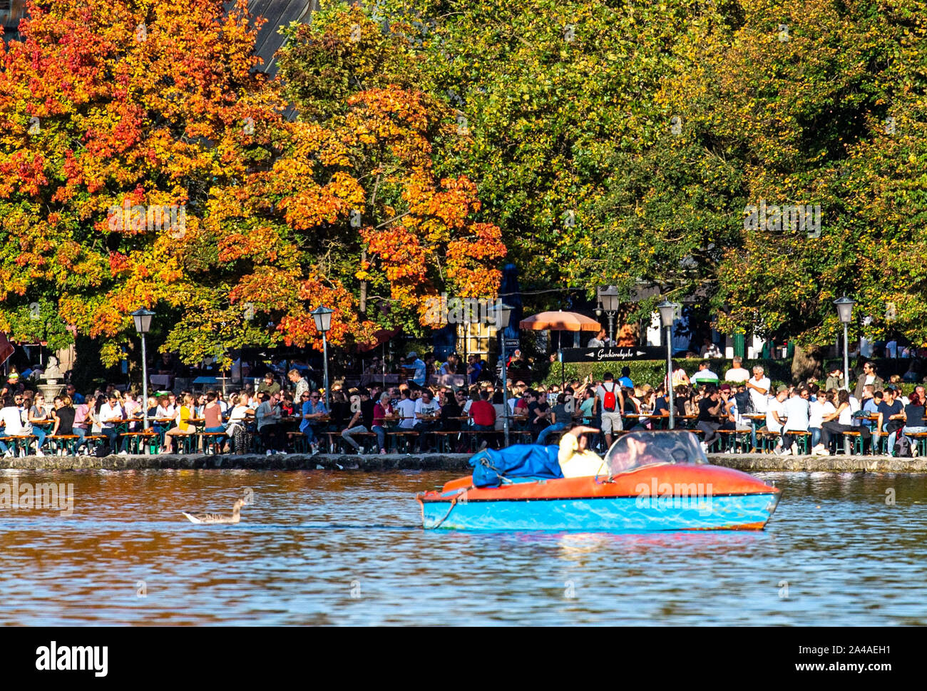 Munich, Germany. 13th Oct, 2019. Persons in pedal boats ride in front of the beer garden from the Seehaus in the English Garden on the Kleinhesseloher See. Credit: Lino Mirgeler/dpa/Alamy Live News Stock Photo