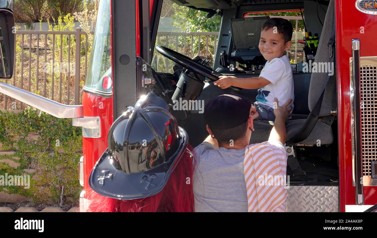 Parents take pictures of their child as they get to explore the fire truck at fire station open house Stock Photo