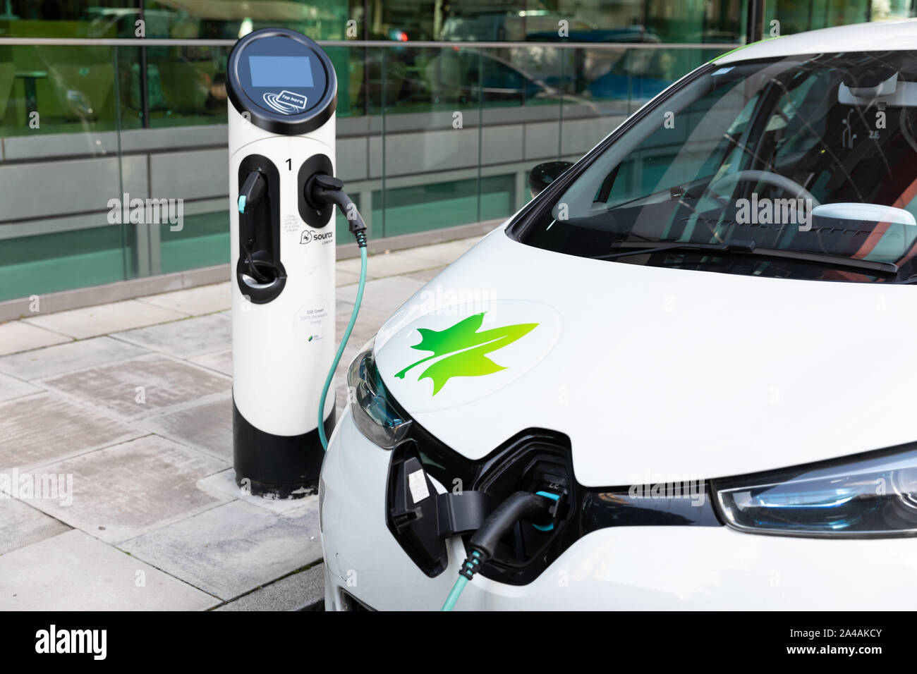 An electric car being charged at an EV charging point on a city street ...