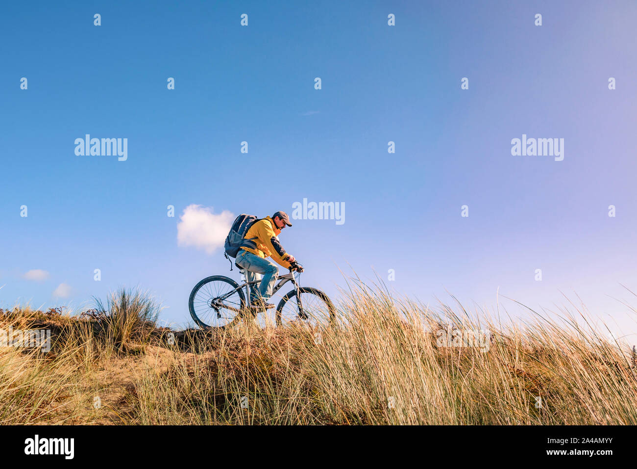 Cycling Ireland. Recreational cyclist with mountain bike and backpack riding downhill in sand