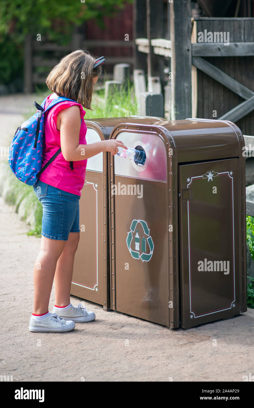 Girl depositing a plastic bottle in a special recycling container Stock Photo