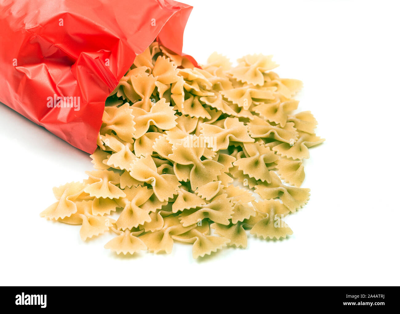 Farfalle pasta dropped from package on white background Stock Photo