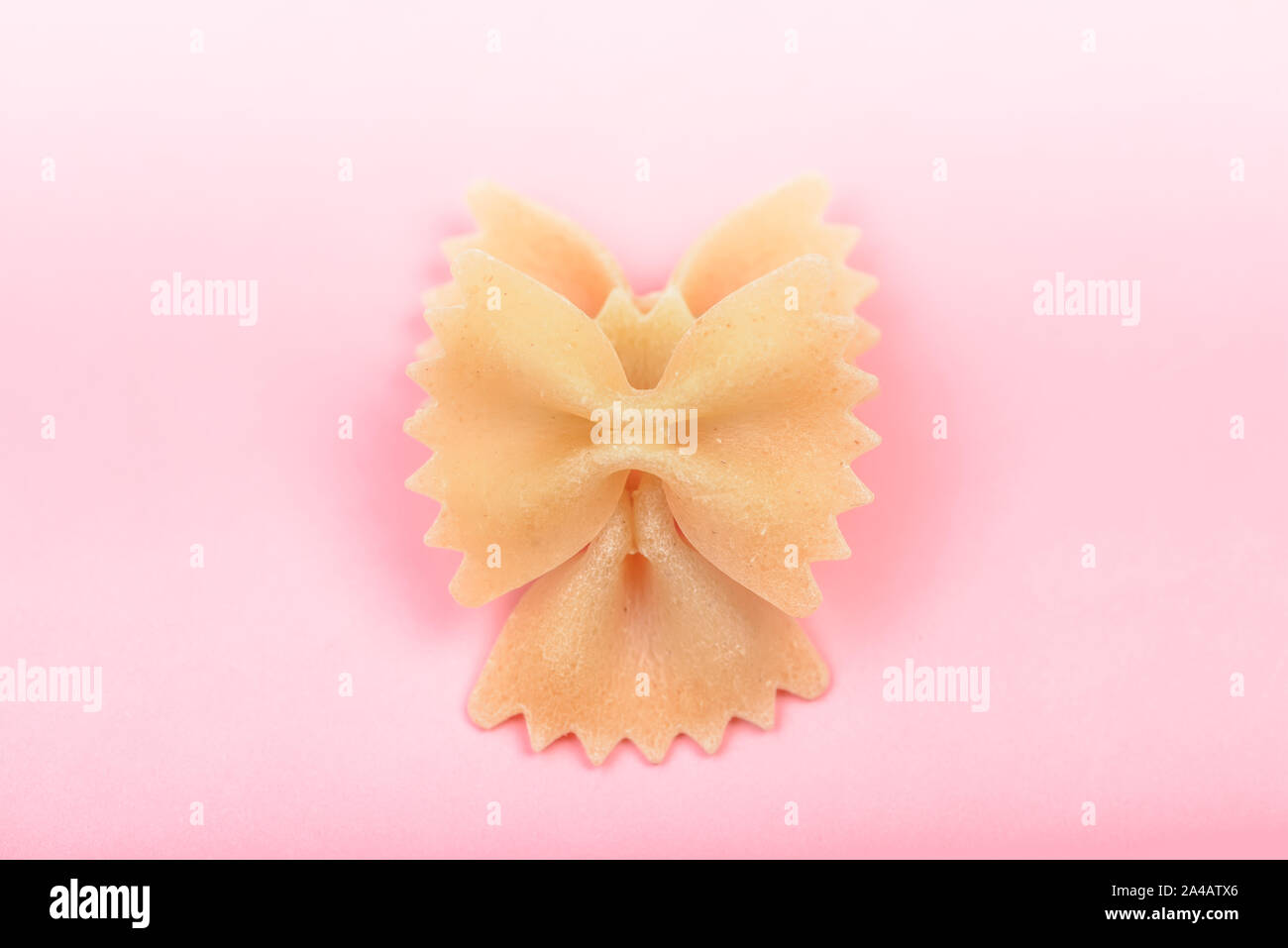 Farfalle tie bow shaped pasta macro on pink background Stock Photo
