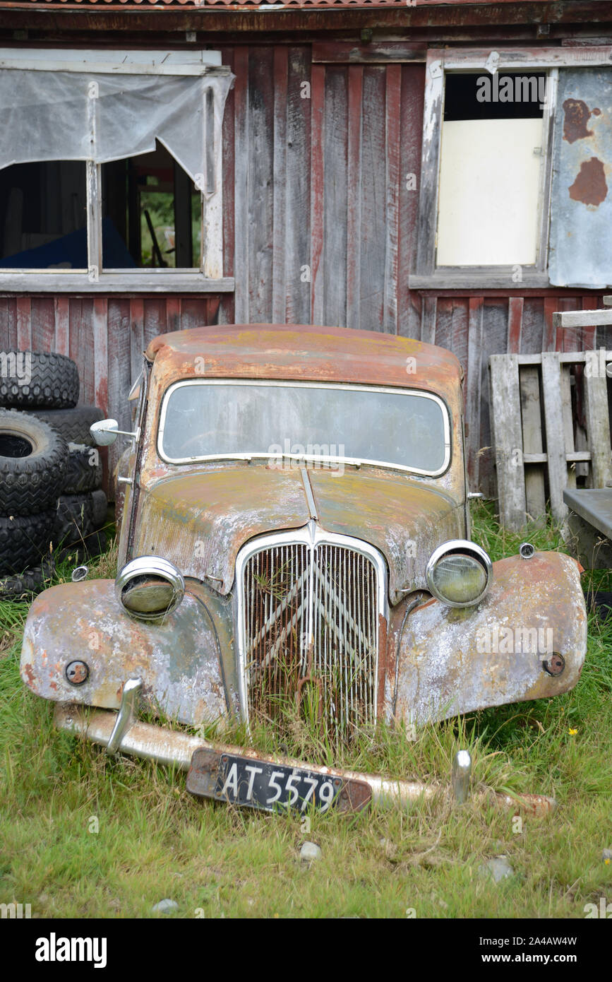 An abandoned car rests next to an old barn in New Zealand Stock Photo