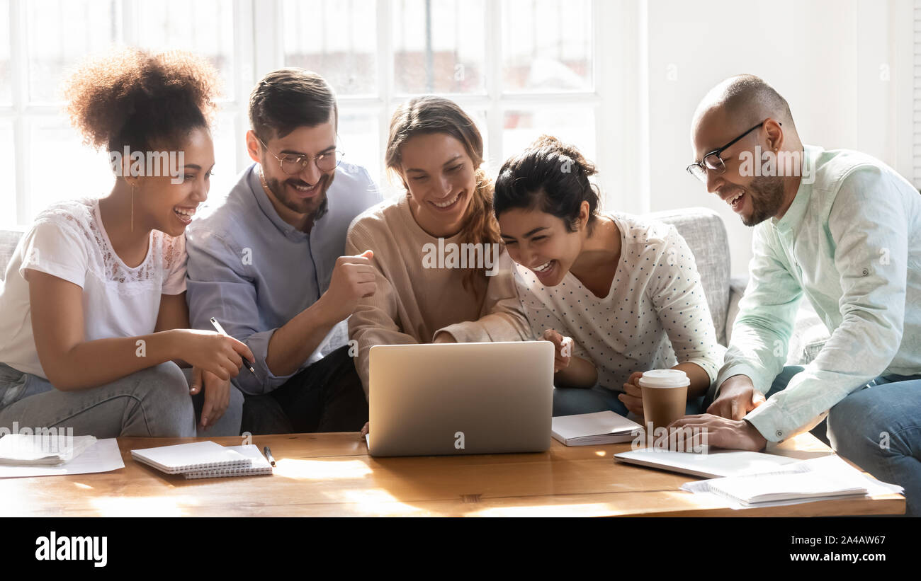 Happy diverse friends watching funny video, using laptop, having fun Stock Photo