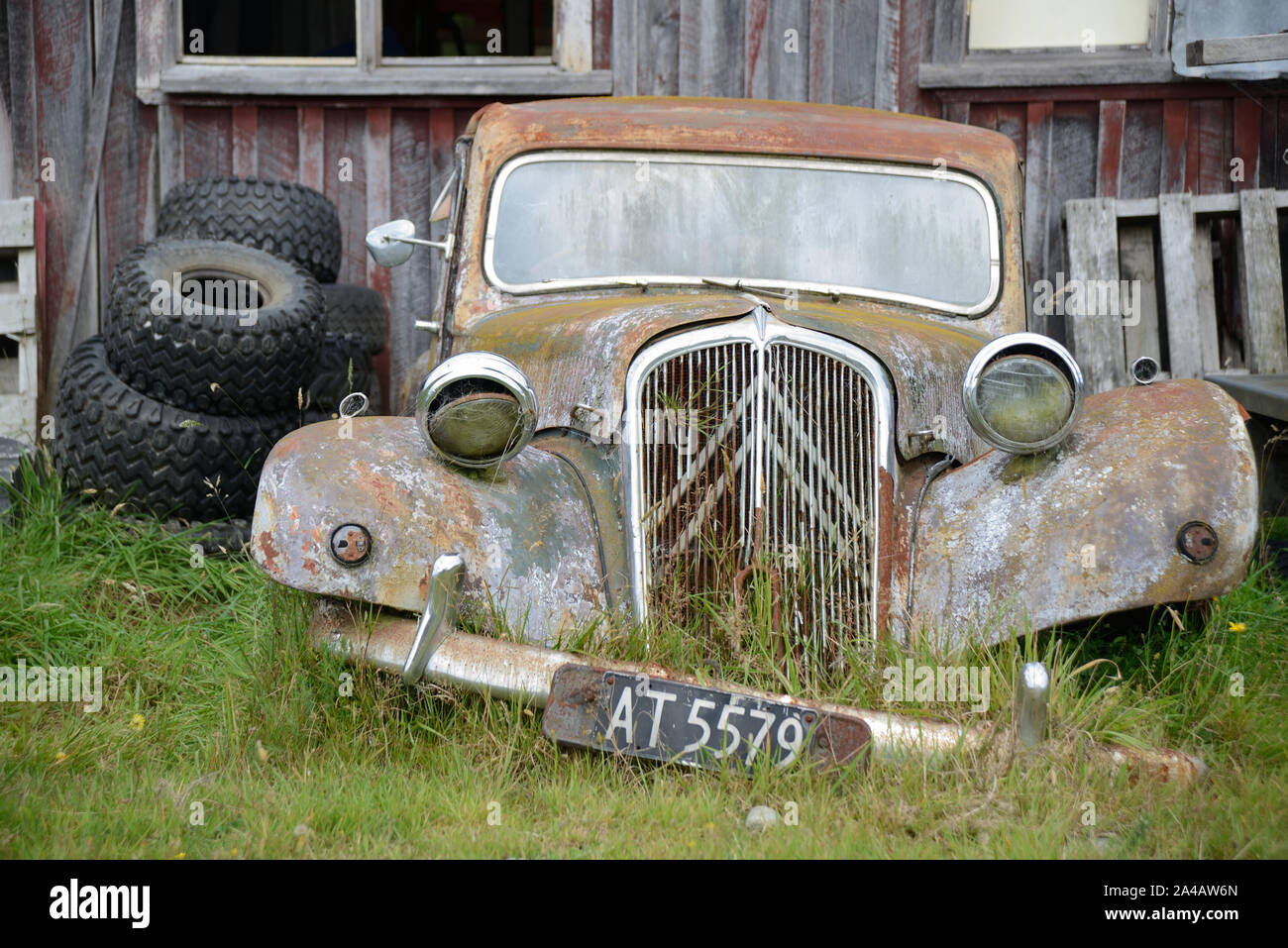 An abandoned car rests next to an old barn in New Zealand Stock Photo