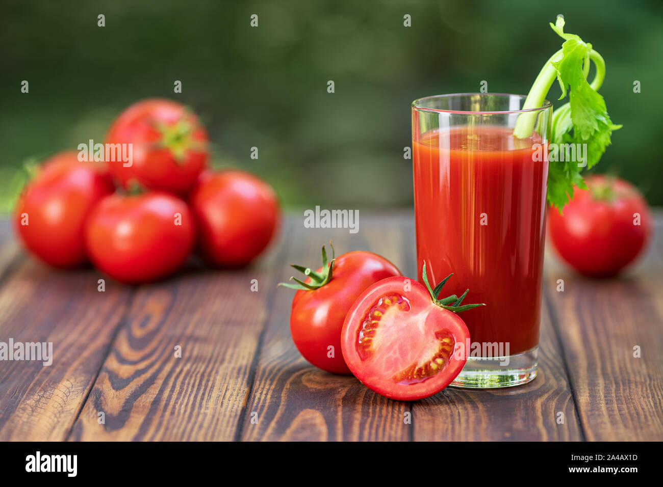 fresh tomato juice in glass with celery stick and heap of ripe vegetables on wooden table outdoors Stock Photo