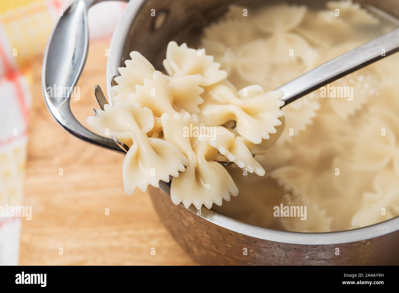 Boiled hot farfalle on the pasta spoon at home kitchen Stock Photo