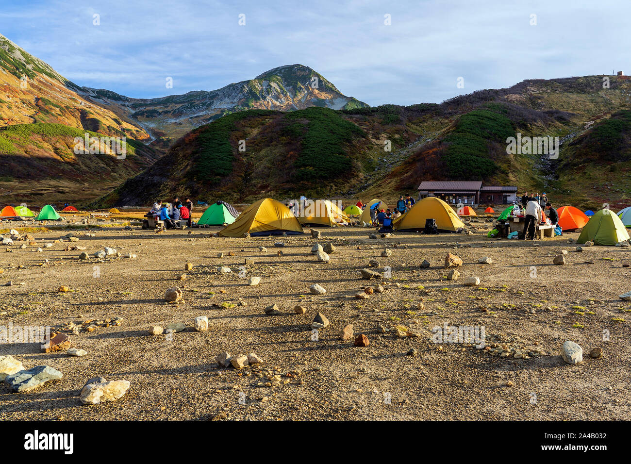 Campsite And Few Colorful Tents Are In The Valley. People Are Preparing Food For Dinner On The Hiking. Outdoor Activities. Stock Photo