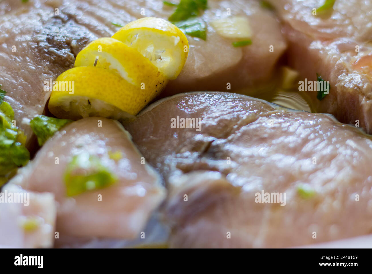 Marinated swordfish in a bowl with lemon, oil, garlic, parsley Stock Photo