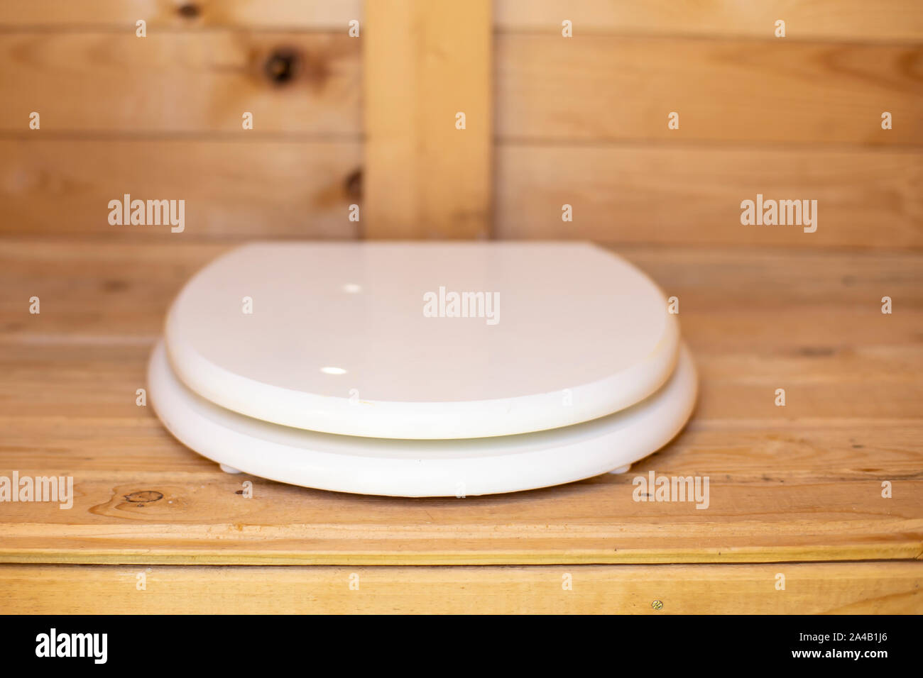 Modern toilet seat with white cover in a wooden, rustic restroom (WC). Close-up. Stock Photo